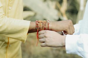 Close-up of hands exchanging colorful Rakhi bracelets during a traditional Indian festival in Kuttanad, Kerala.